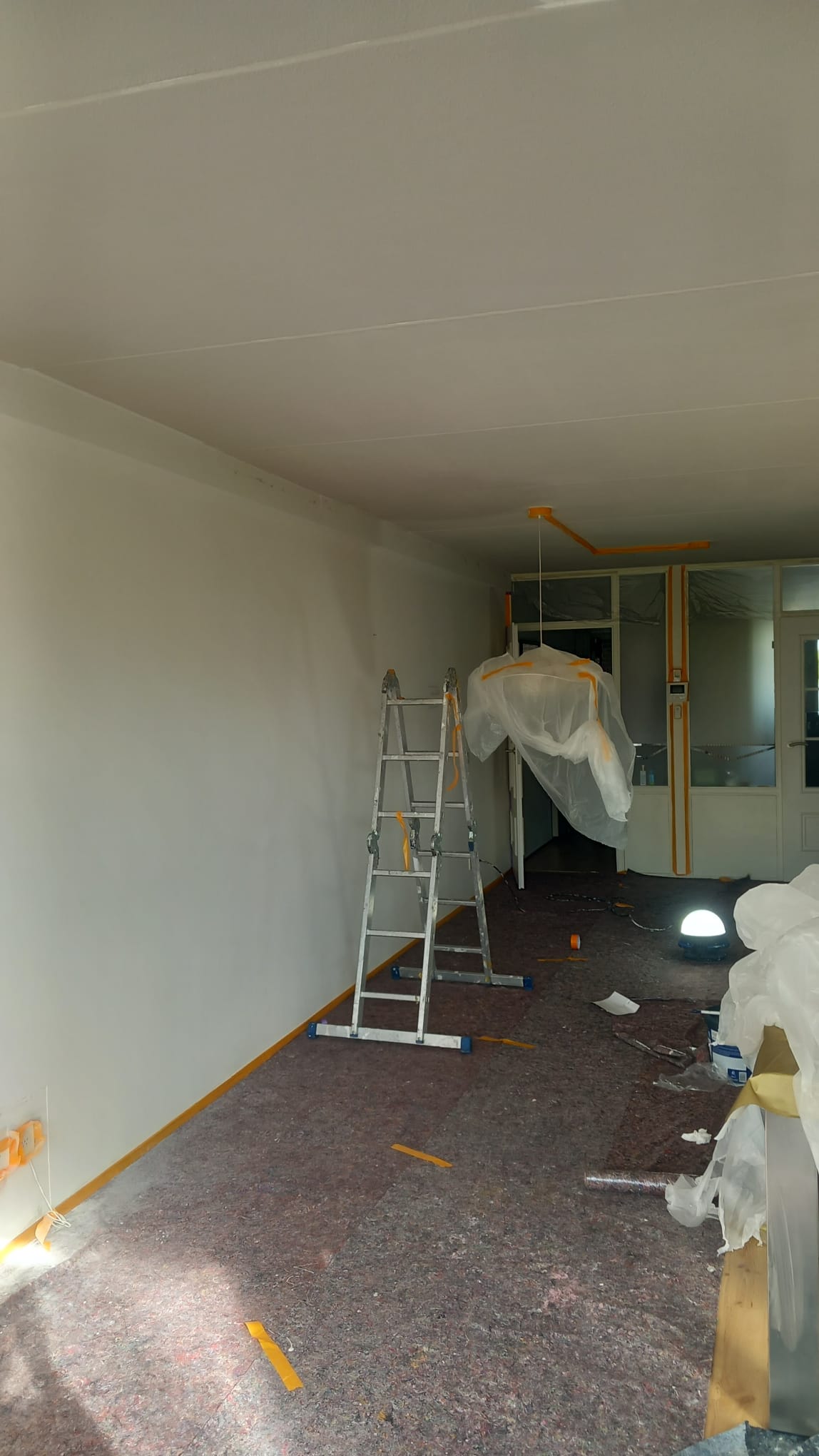 Hand van schilder met verfroller boven een verfemmer